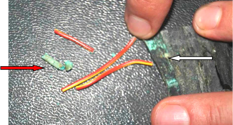 Фото 25. Изоляция электропроводки в месте разрыва  зелёного цвета (показаны белой стрелкой) и фрагмент остатка окисленной электропроводки (показано красной стрелкой)   .